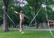 Die Abbildung zeigt einen jungen Mann beim slacklinen iim Stadtpark.