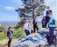 Sechs Menschen stehen auf Felsen in der Sächsischen Schweiz um ein Picknick.