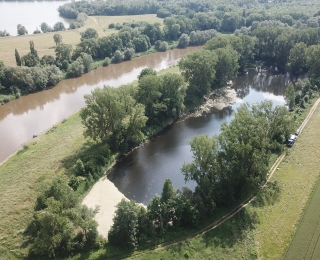 Luftbildaufnahme eines langgesteckten Altabgrabungs-Gewässers ("Lohbuschteich" in Bad Oeynhausen), der parallel zu einem Fluss (Weser) liegt. Auf der gegenüberliegenden Flussseite ist ein Teil eines weiteren Abgrabungsgewässers zu sehen.
