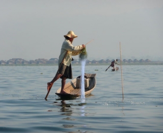 Fischer auf kleinen Boot mit Fischernetzen