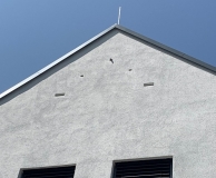 Graue Hausfassade vor blauem Himmel