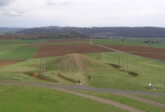 Inmitten einer agrarisch genutzten Landschaft ist eine keltische Hügelanlage zu sehen. Das Bild wurde in der Wetterau aufgenommen.