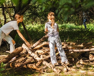 Kinder spielen mit Holzstämmen