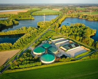Eine Biogasanlage umgeben von Grünflächen und Seen
